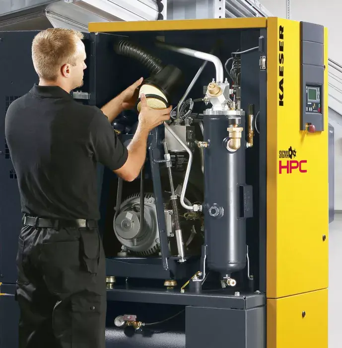 Technician removing or installing an air filter inside a Kaeser industrial compressed air system during scheduled maintenance.